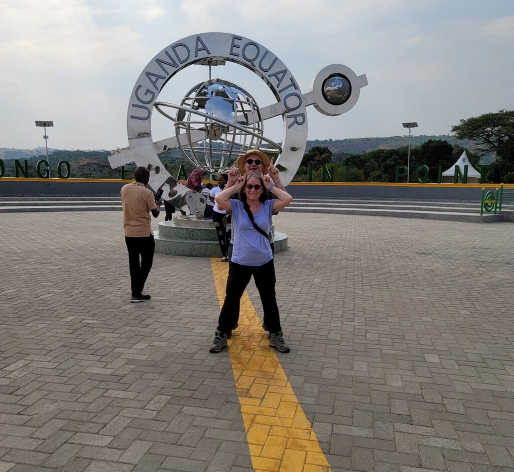 Standing at the Uganda equator sign on the way to Queen Elizabeth National Park